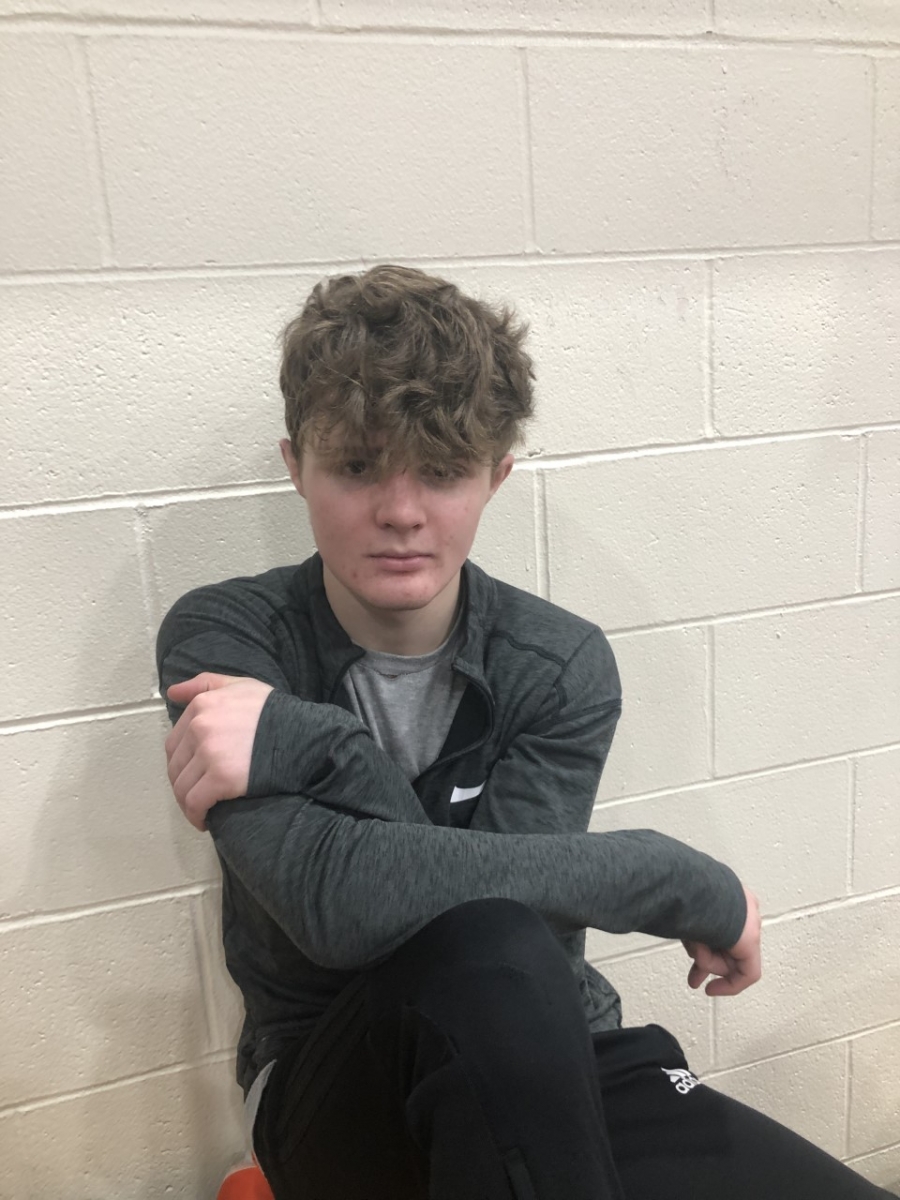 boy sitting against brick wall